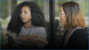 Two women talk at a meeting